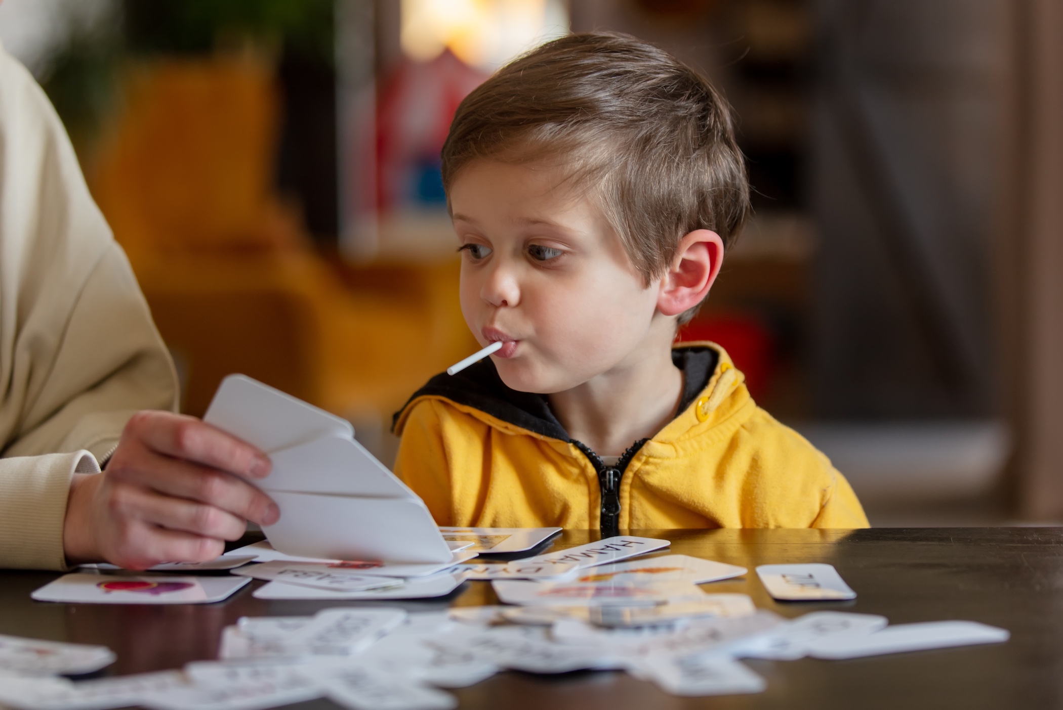little boy learns words from cards under the ABA therapy program at home at the table
