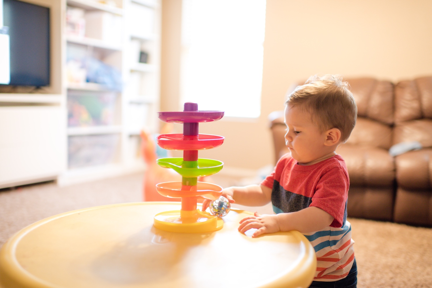 Toddler playing with a toy in a living room.
