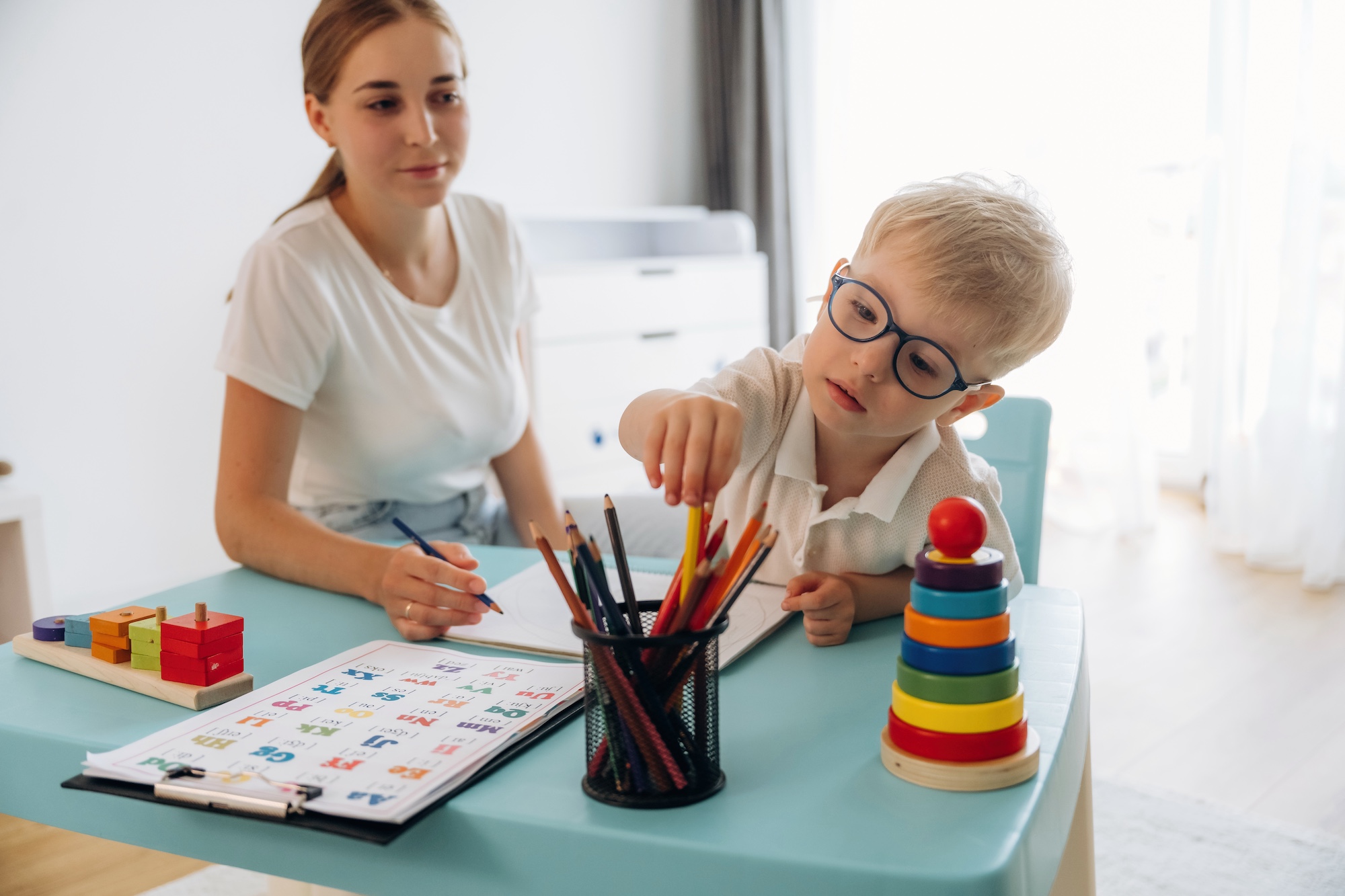 Little boy learning how to draw under the supervision of an adult.
